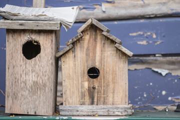 Two old wooden birdhouses on cracked wooden wall with peeling paint, rustic bird feeders close up side view