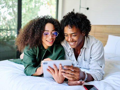 Portrait of a lovely young couple together holding a tablet in bed at home