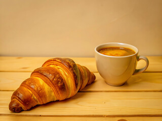 Freshly baked croissant with coffee on a rustic wooden table