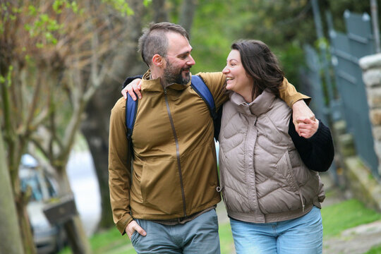 Happy middle-aged couple walking together outdoors in spring or autumn, enjoying nature and spending time hiking or exploring the park. - Powered by Adobe
