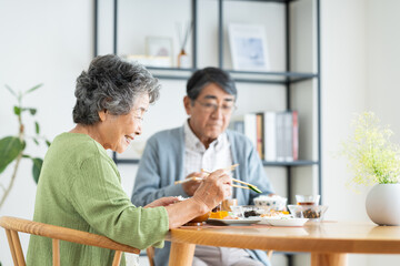 家で朝食を食べるシニアの夫婦