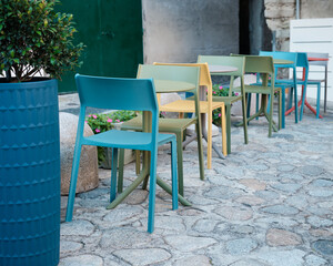 Colorful outdoor chairs and tables in a cozy Mediterranean cafe patio, modern urban design and summer lifestyle.
