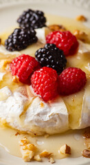 Melted camembert cheese topped with raspberries, blackberries, walnuts and honey. Healthy dessert. Shallow depth of field.