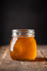 Jar of honey on wooden table with dark background. Natural food.