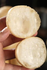 Hand Holding Torn Bread Roll Showing Soft White Interior Texture