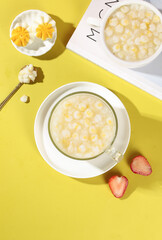 Fresh white corn porridge soup with boiled egg and strawberries on yellow background