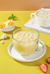 Fresh Corn Soup in Glass Cup with Boiled Egg Garnish on Yellow Background
