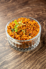 Glass bowl with creamy base and golden breadcrumb topping, garnished with fresh herbs. Rustic presentation on wooden surface. Ideal for gourmet or lifestyle food themes.