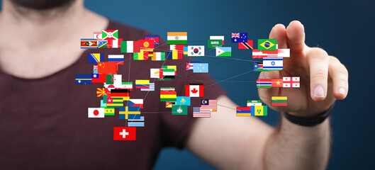 A person's finger touching a digital network of flags representing countries worldwide, signifying global unity and international relations. Ide