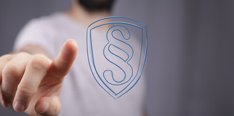 Hand pointing at digital shield with legal paragraph symbol.  Security, law, justice concept.