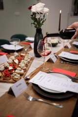 catering scene with wine being served on a glass and food on a well prepared the table with menu. 