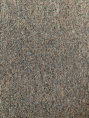 Detailed full-frame background of a dense woven loop pile carpet featuring a subtle pattern in mixed brown, gray, and muted green yarns. Interior Design concept