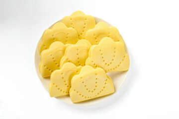 Handmade Heart-Shaped Yellow Crackers with Ruffled Edges and Decorative Holes on White Background