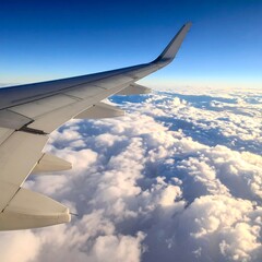 Fototapeta premium Airplane wing soaring through fluffy clouds and blue skies