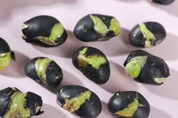 Black beans with green sprouts sprouting on pink background - healthy cooking ingredients