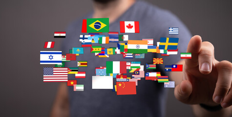 Person pointing at a selection of world flags, representing international relations, global...