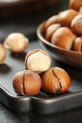 Fresh Hazelnuts with Cracked Shells and White Kernels on Dark Surface