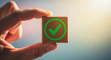 Hands hold small cube with green checkmark symbol signifying success and approval in business