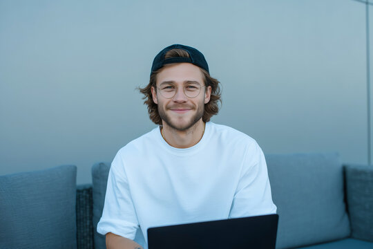 Happy young man working on laptop outdoors in urban setting, freelance remote work lifestyle