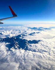 Fototapeta premium Aerial view of a snow-capped mountain range above clouds