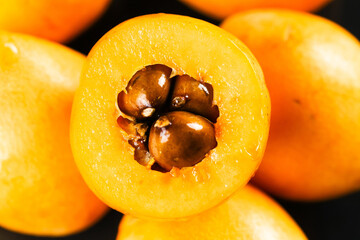 Fresh Loquat Fruit Cut in Half Showing Seeds and Golden Yellow Flesh
