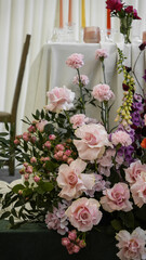 Colorful wedding flower arrangement in front of the bride and groom's table. Ranunculus, gerbera, snapdragons, roses, carnations, peonies
