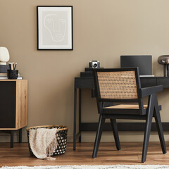 Modern interior design of home office space with stylish chair, desk, commode, black mock up poster frame, lapatop, book, office organizer and elegant presonal accessories in home decor. Template.