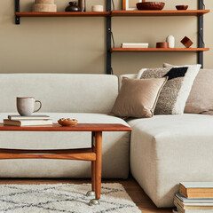 Stylish interior of living room with design wooden coffee table, beige sofa, cup of coffee, book, decoration and elegant accessories in stlish home decor. Template.