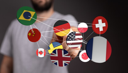 A person's hand reaching out to connect different world flags representing digital global network,...