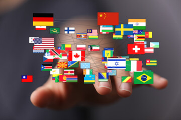 A hand holds various flags of different nations, signifying international relationships and global...