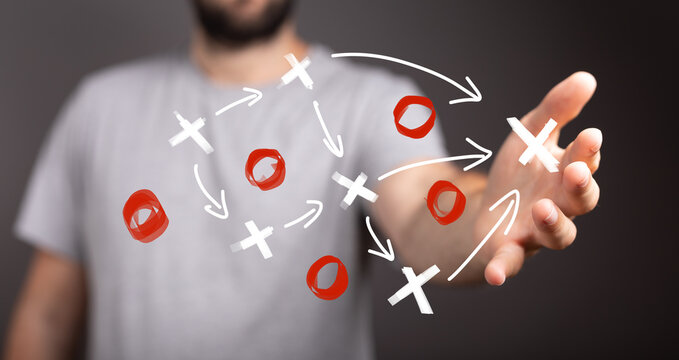 Man's hand displays a strategic plan with Xs and Os, visualizing decision-making and problem-solving.