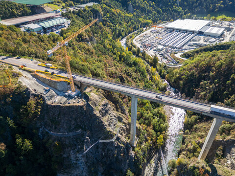 The Brenner Base Tunnel "BBT" construction site in Varna, Alto Adige, with cranes and machinery set against the stunning backdrop of the Alps.
