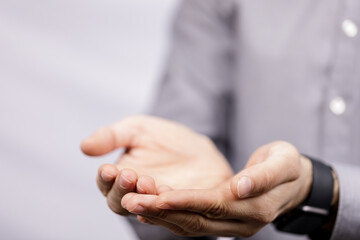 Obraz premium Man with open hands offering something concept on gray background. Gesturing with hands, providing support or help or receiving with palm up.