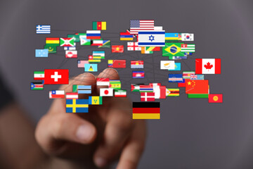 Hand touching network of global flags representing international relations, communication, travel, and connections. Worldwide community, collabo