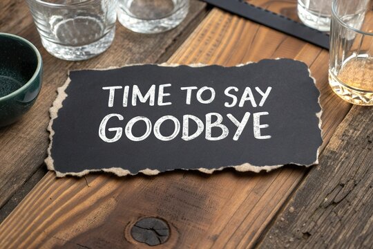 Rustic farewell sign on wooden table surrounded by glassware, evoking nostalgia and reflection