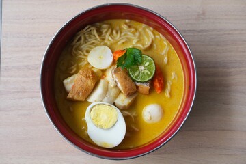 A vibrant bowl of Mie Kari, a traditional Indonesian noodle soup made with yellow curry broth.