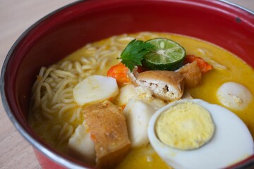 A vibrant bowl of Mie Kari, a traditional Indonesian noodle soup made with yellow curry broth.