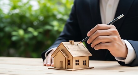 Real estate agent reviews property plans holding pen near miniature house model outdoor setting