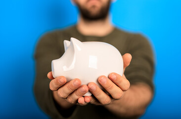 Person holding a white piggy bank. This image represents savings, investment, wealth, and financial...