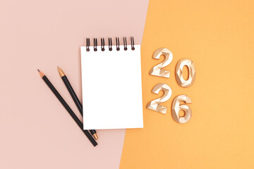 2026 New Year concept with place for text. Clean notepad mockup and golden numbers on a beige background.