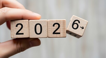 Hand turning wooden blocks revealing the year 2026 with a partially flipped block for the next year