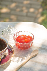 Berry jam in a glass bowl on a table with a tablecloth in a summer garden