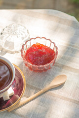 Berry jam in a glass bowl on a table with a tablecloth in a summer garden
