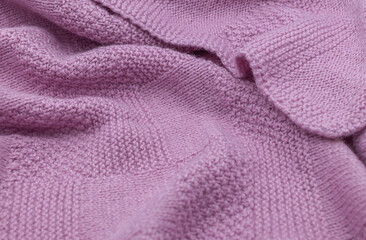 Purple knit fabric as a background. Wool knit texture. Purple knitted fabric surface with soft folds. Textile material for design. Purple knitted texture. 