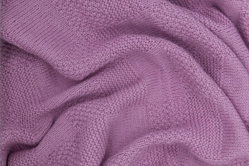 Purple knit fabric as a background. Wool knit texture. Purple knitted fabric surface with soft folds. Textile material for design. Purple knitted texture. 