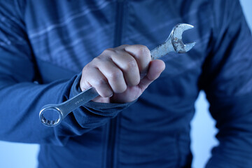 A person is holding a wrench in their hand. firmly grips silver double-ended wrench for tighteninga worker, builder, repairman, handyman, holding wrench. Workshop equipment