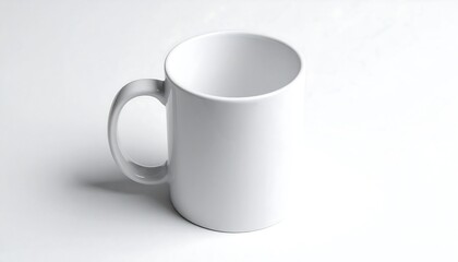 Obraz premium A clean, empty, cylindrical ceramic cup with a handle sits on a white surface, lit from above for a simple studio shot