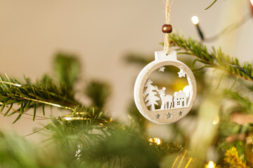 Close up shot of a Christmas tree ornament with deer, house and stars hanging on a Christmas tree branch. Holiday decorations. Festive season. W © vegefox.com