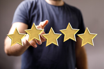 A person's hand points at golden star icons, indicating rating, positive feedback, or customer...