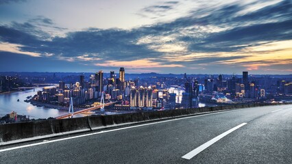 Chongqing Cityscape at Dusk from Elevated Road with Cloudy Sky Lit Buildings and River in...